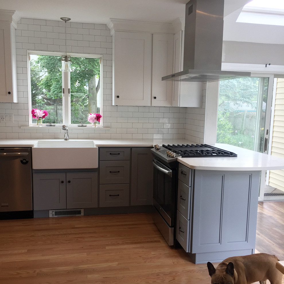Kitchen - small transitional light wood floor and beige floor kitchen idea in Providence with a farmhouse sink, shaker cabinets, white cabinets, white backsplash, subway tile backsplash, stainless steel appliances, a peninsula, white countertops and marble countertops