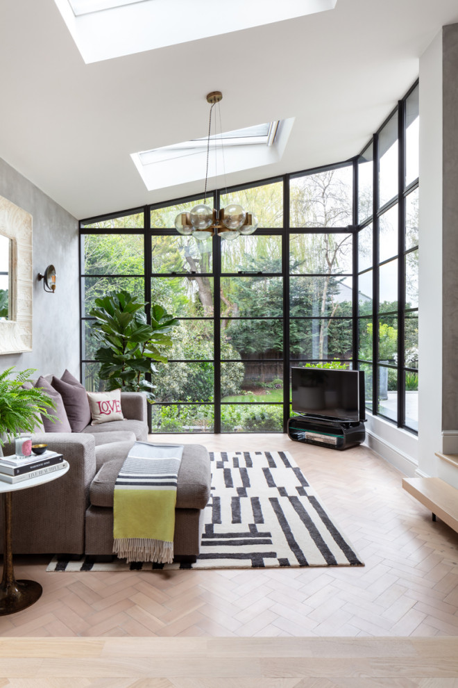 Exempel på ett mellanstort modernt allrum med öppen planlösning, med grå väggar, ljust trägolv, en fristående TV och brunt golv