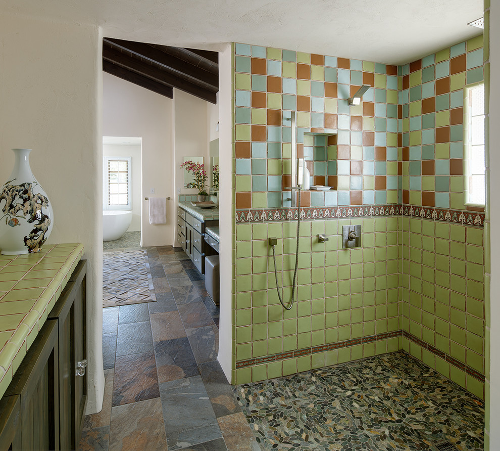 This is an example of a master bathroom in San Diego with ceramic tile, shaker cabinets, dark wood cabinets, a curbless shower, multi-coloured tile, white walls, pebble tile floors, tile benchtops, multi-coloured floor, an open shower and green benchtops.