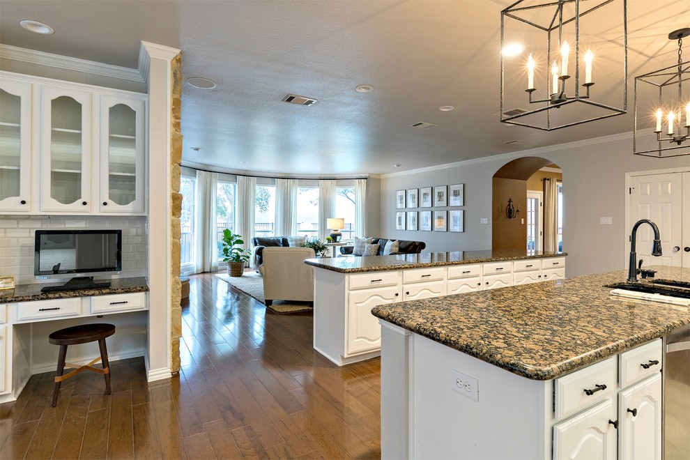 Example of a large transitional galley medium tone wood floor open concept kitchen design in Dallas with an undermount sink, white cabinets, granite countertops, white backsplash, subway tile backsplash, stainless steel appliances and two islands