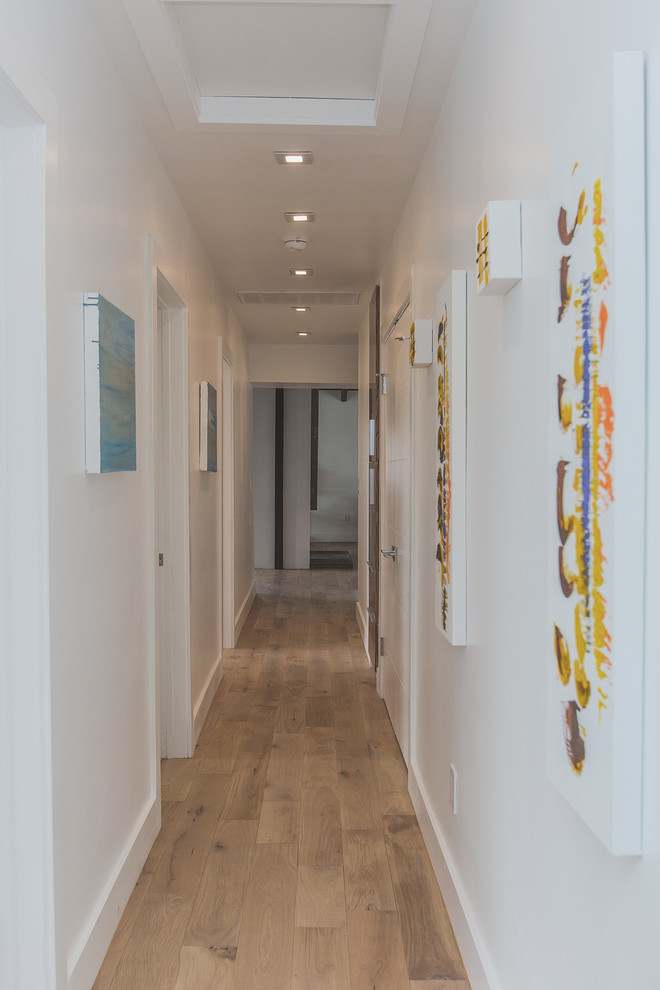 Small modern hallway in Los Angeles with white walls and light hardwood floors.