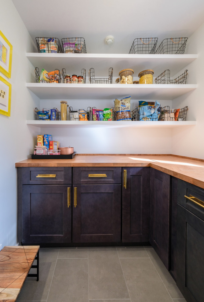 Kitchen pantry - mid-sized modern u-shaped porcelain tile and gray floor kitchen pantry idea in New York with a farmhouse sink, shaker cabinets, blue cabinets, wood countertops, white backsplash, porcelain backsplash, stainless steel appliances, an island and brown countertops