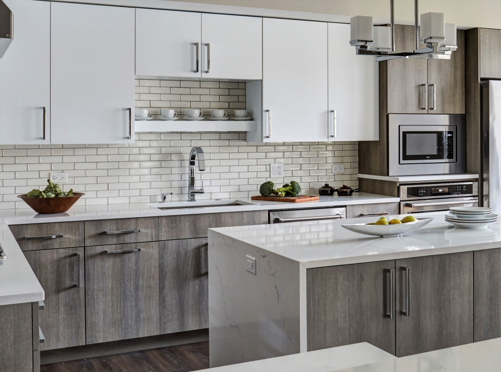 Photo of a mid-sized contemporary l-shaped eat-in kitchen in Chicago with a single-bowl sink, flat-panel cabinets, white cabinets, quartz benchtops, white splashback, ceramic splashback, vinyl floors, with island and white benchtop.