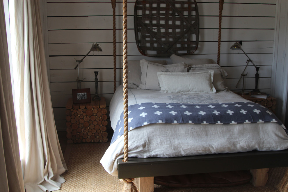 This is an example of a small country guest bedroom in Nashville with white walls and light hardwood floors.