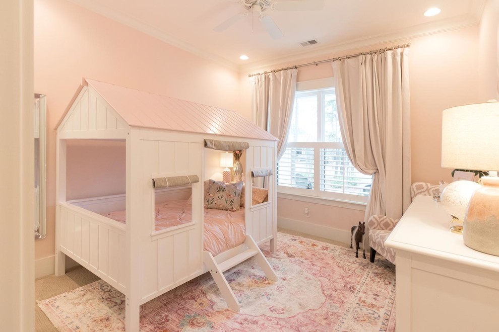 This is an example of a mid-sized transitional kids' bedroom for kids 4-10 years old and girls in Atlanta with pink walls, carpet and beige floor.