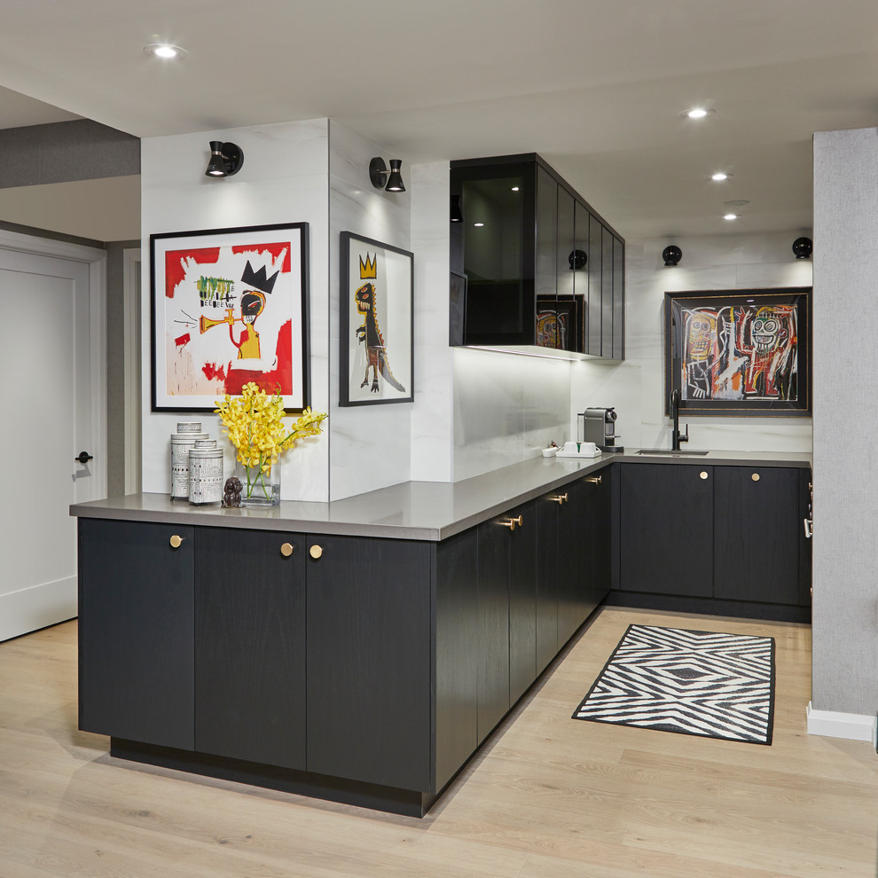 This is an example of a small modern u-shaped eat-in kitchen in Toronto with flat-panel cabinets, black cabinets, quartz benchtops, white splashback, porcelain splashback, panelled appliances, light hardwood floors, no island, grey floor and grey benchtop.