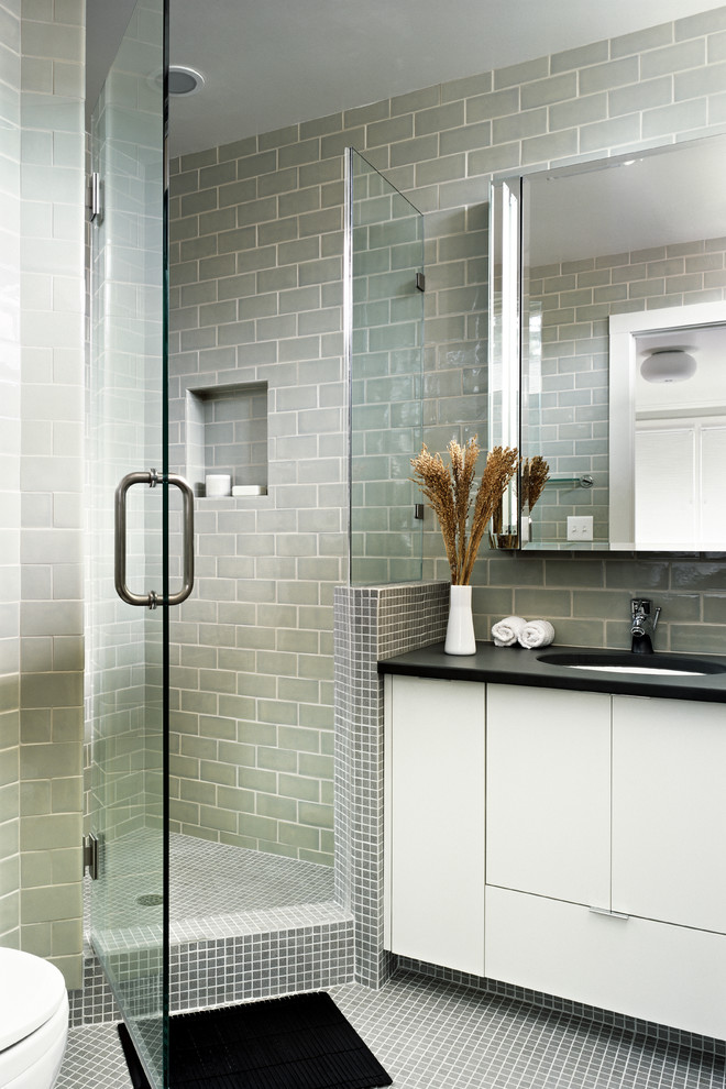 This is an example of a mid-sized modern master bathroom in San Francisco with flat-panel cabinets, white cabinets, a corner shower, a two-piece toilet, green tile, ceramic tile, green walls, mosaic tile floors, an undermount sink and soapstone benchtops.
