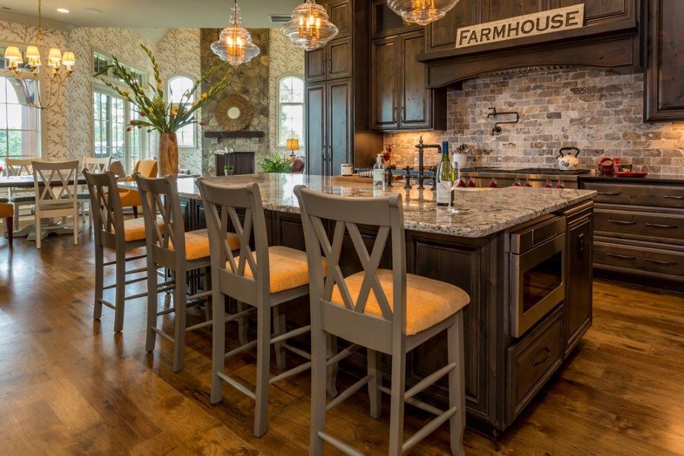 This is an example of a large transitional eat-in kitchen in Charlotte with raised-panel cabinets, dark wood cabinets, granite benchtops, light hardwood floors and with island.