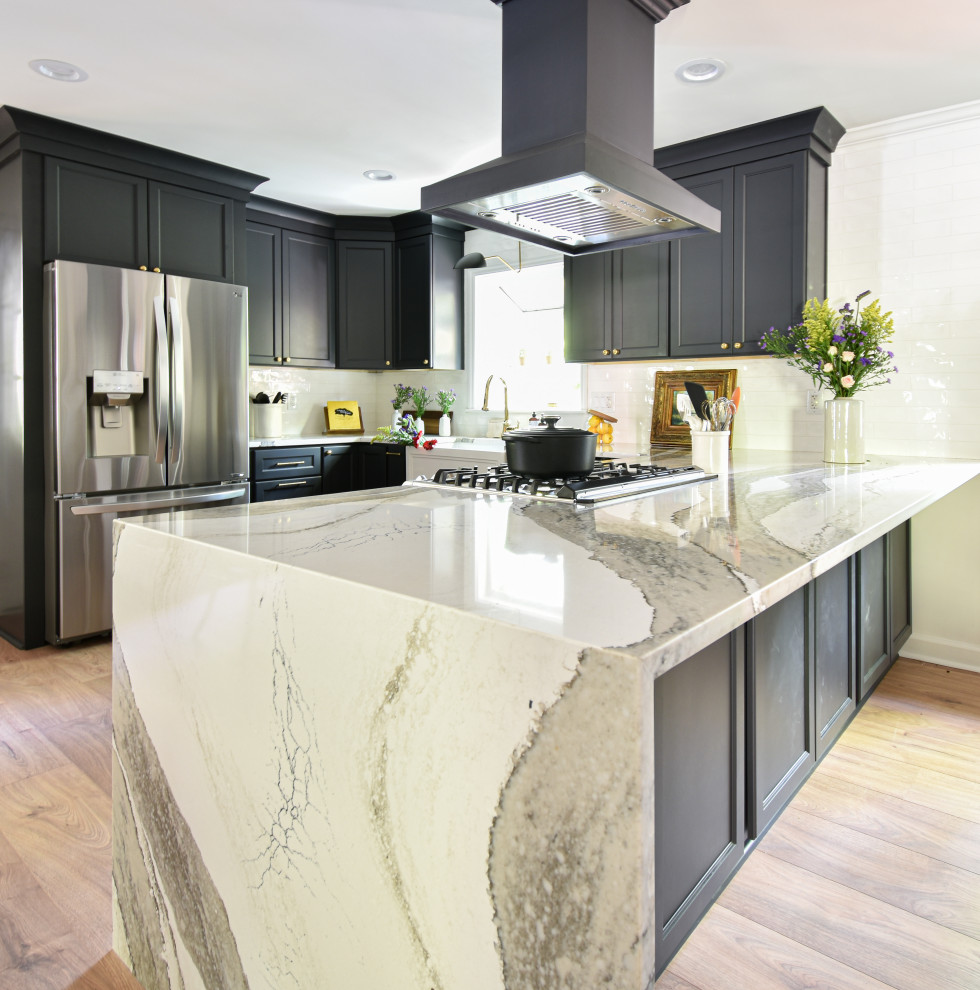 Inspiration for a mid-sized transitional u-shaped laminate floor open concept kitchen remodel with a farmhouse sink, black cabinets, quartzite countertops, white backsplash and a peninsula