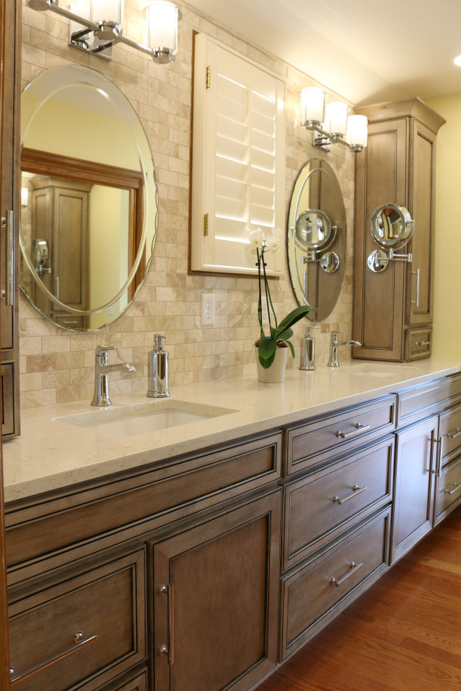 This is an example of a mid-sized transitional master bathroom in Denver with flat-panel cabinets, medium wood cabinets, an alcove shower, a one-piece toilet, beige tile, marble, beige walls, medium hardwood floors, an undermount sink, engineered quartz benchtops, brown floor, a hinged shower door, beige benchtops, a double vanity, a built-in vanity and vaulted.