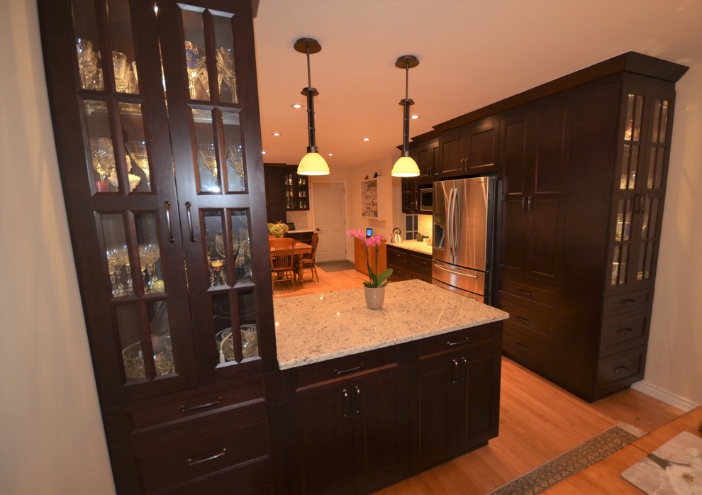 Mid-sized transitional galley medium tone wood floor and brown floor eat-in kitchen photo in Ottawa with recessed-panel cabinets, dark wood cabinets, granite countertops, gray backsplash, stainless steel appliances, a double-bowl sink, porcelain backsplash, a peninsula and beige countertops
