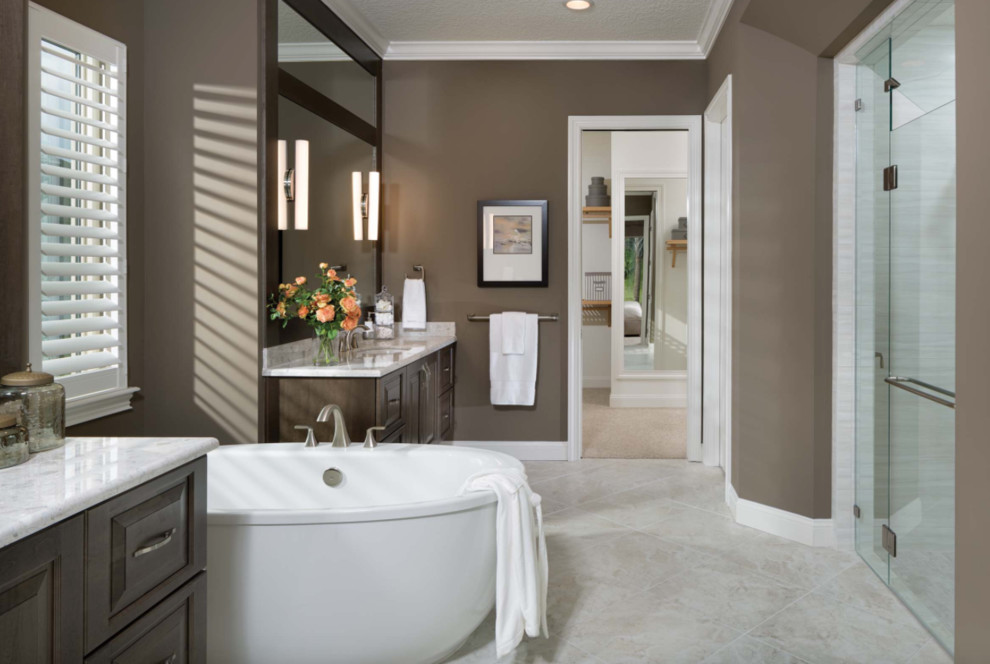 Inspiration for a large master bathroom in Miami with raised-panel cabinets, dark wood cabinets, a freestanding tub, an alcove shower, brown walls, marble floors, an undermount sink, marble benchtops, beige floor and a hinged shower door.