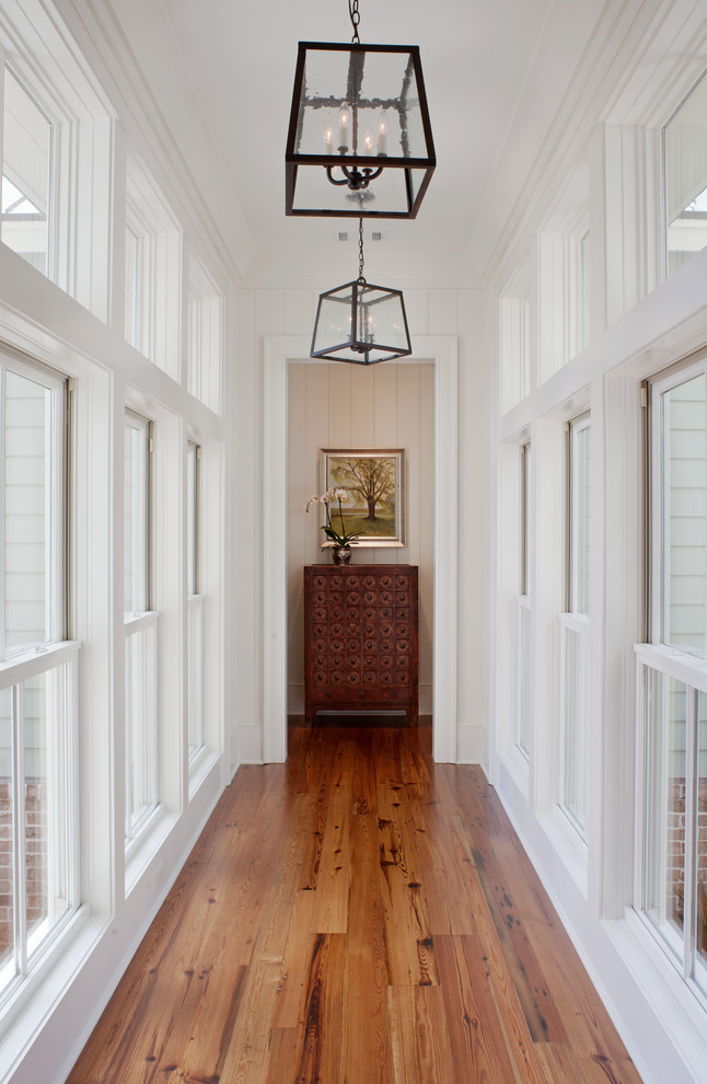 Photo of a transitional hallway in Other with white walls and medium hardwood floors.