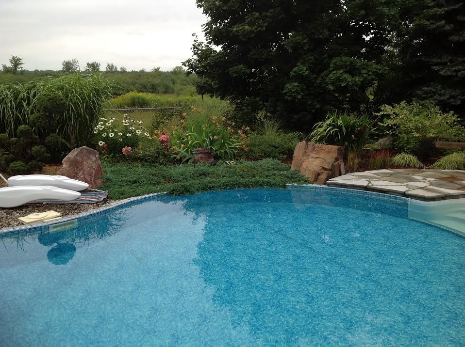Example of a large transitional backyard stone pool design in Ottawa
