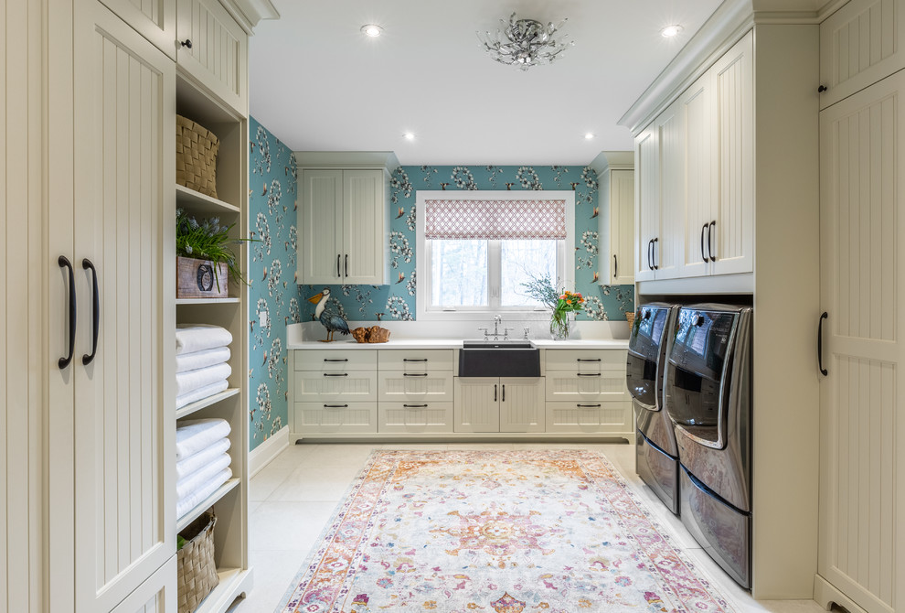 Design ideas for a country u-shaped dedicated laundry room in Toronto with a farmhouse sink, recessed-panel cabinets, white cabinets, blue walls, a side-by-side washer and dryer, beige floor and white benchtop.