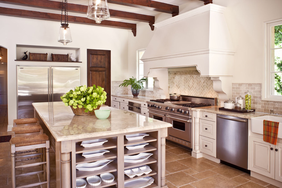Inspiration for a mediterranean kitchen in Los Angeles with raised-panel cabinets, beige cabinets, stainless steel appliances and travertine floors.