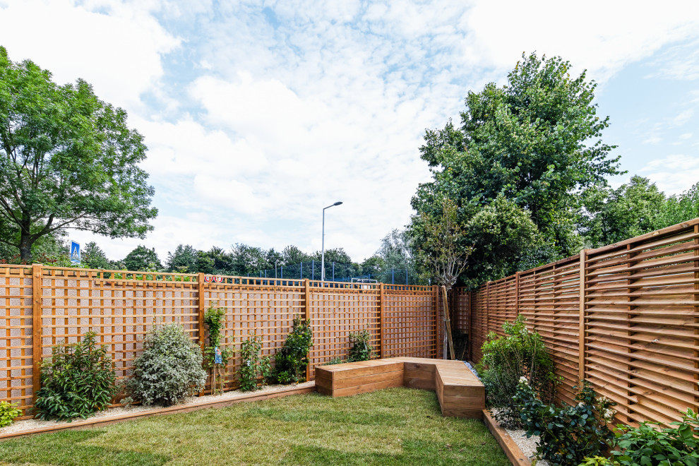 Réalisation d'un jardin arrière design de taille moyenne avec des solutions pour vis-à-vis, une exposition ensoleillée, une terrasse en bois et une clôture en bois.