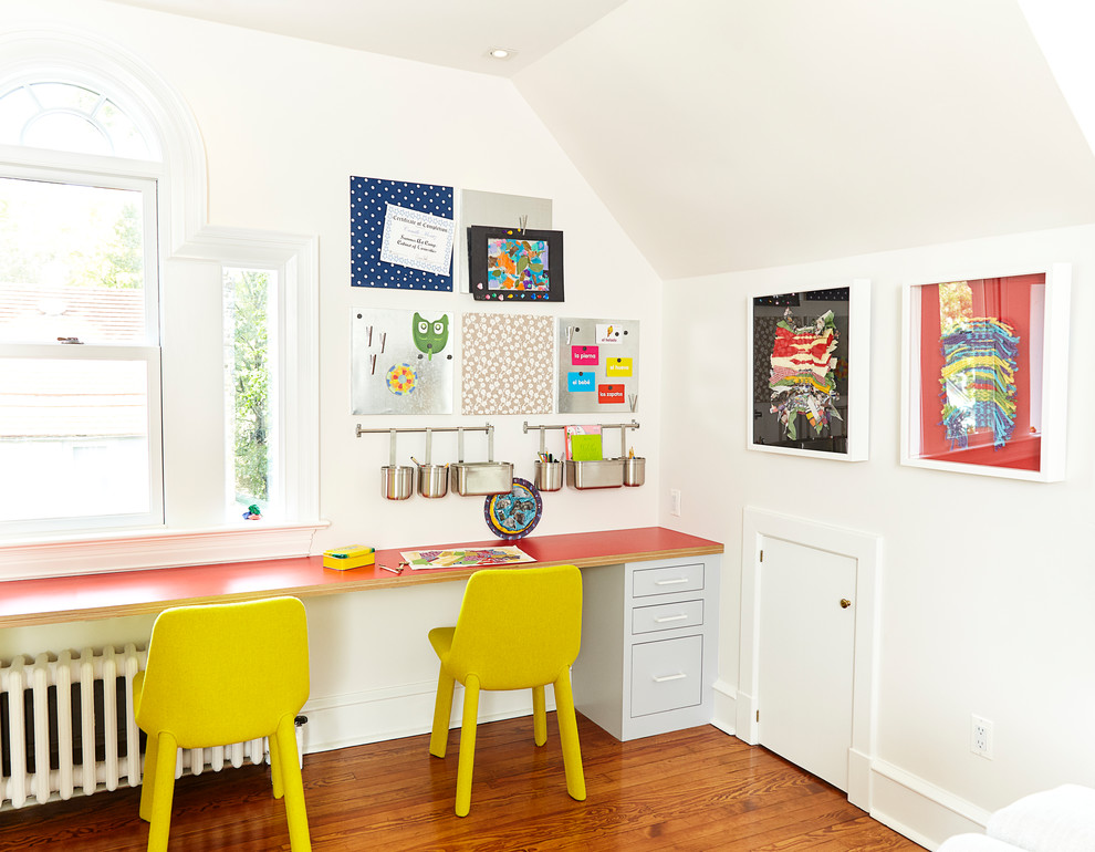 Photo of a large modern gender-neutral kids' playroom for kids 4-10 years old in New York with white walls, medium hardwood floors and brown floor.