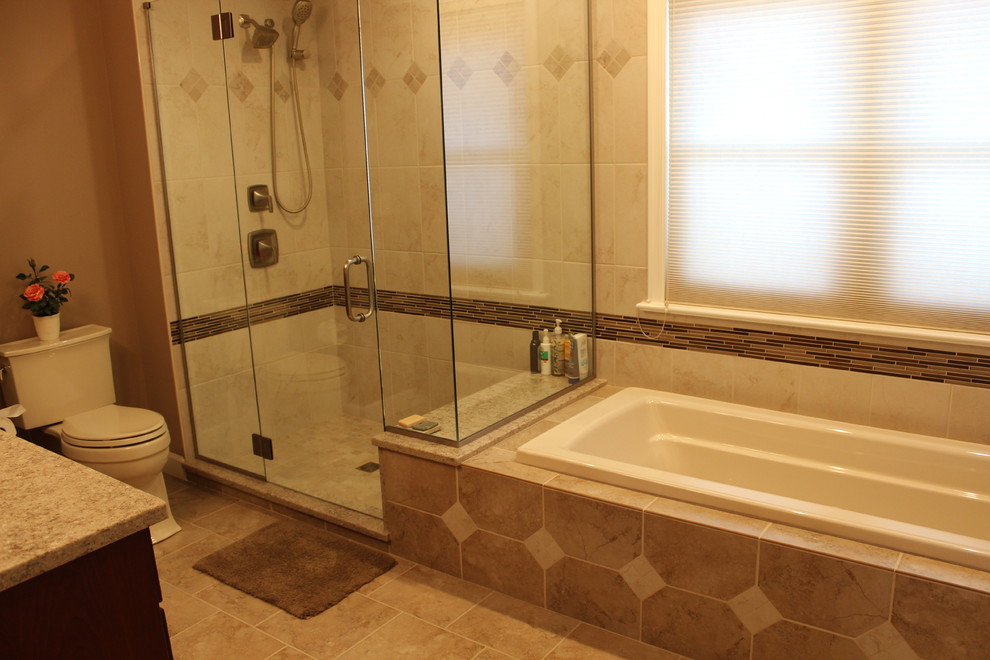 Inspiration for a mid-sized transitional master bathroom in Other with raised-panel cabinets, medium wood cabinets, a drop-in tub, a corner shower, a two-piece toilet, beige tile, porcelain tile, brown walls, porcelain floors, a drop-in sink, granite benchtops, brown floor, a hinged shower door and beige benchtops.