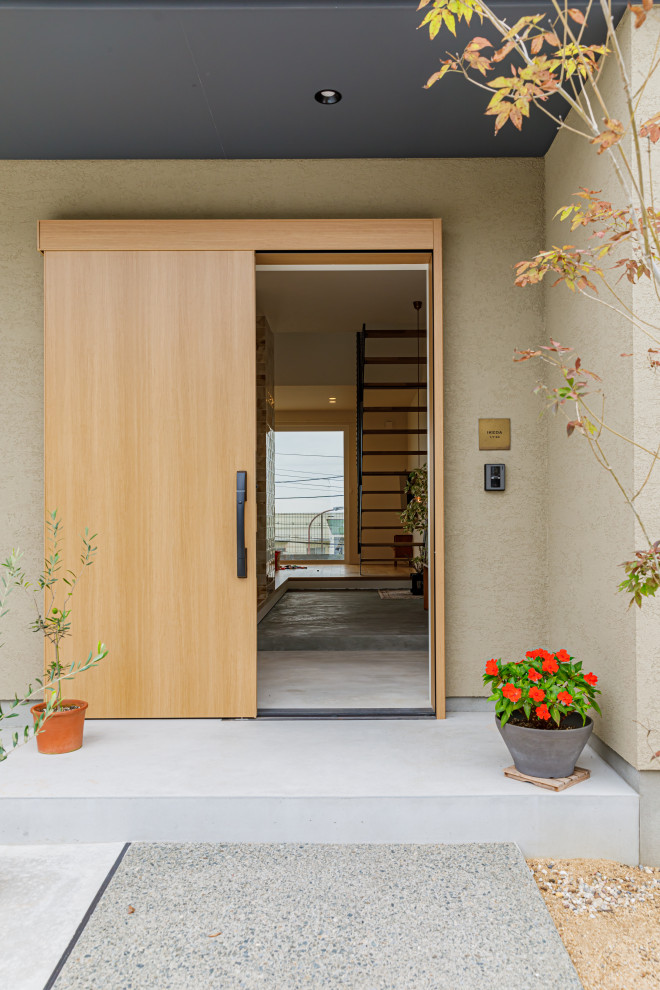 Photo of a mid-sized modern front door with beige walls, a sliding front door, a light wood front door, grey floor, wallpaper and wallpaper.