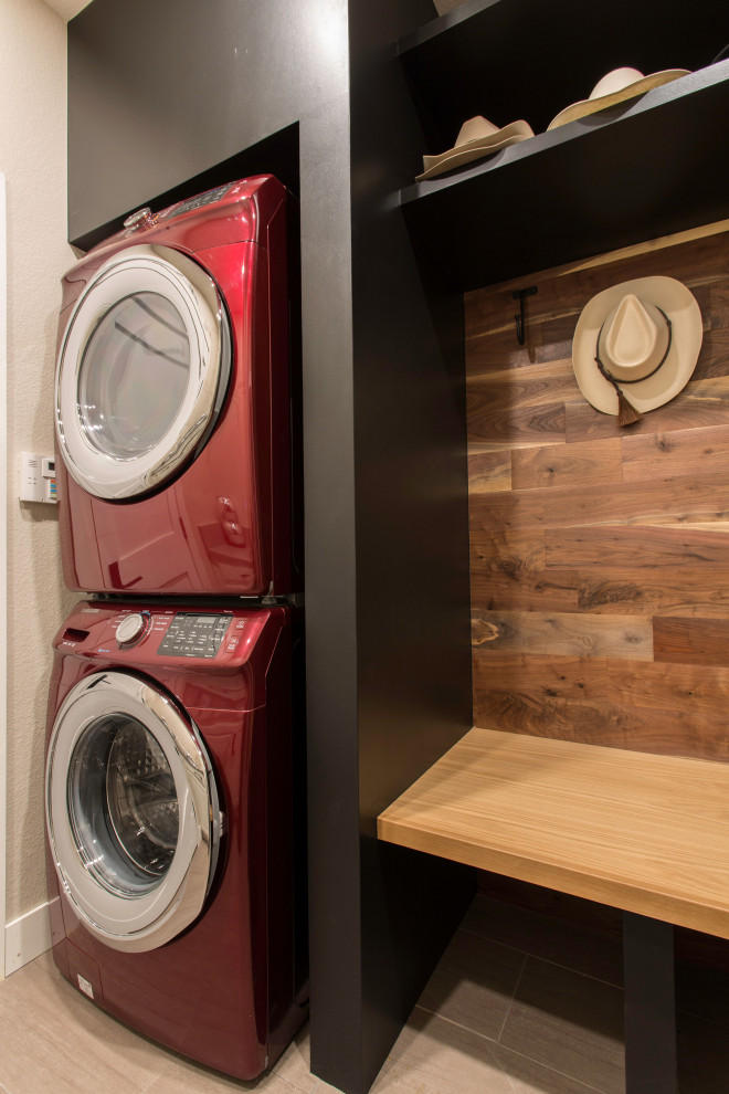 This is an example of a small transitional utility room in Denver with wood benchtops, black walls, porcelain floors, a stacked washer and dryer, grey floor, brown benchtop and wood walls.