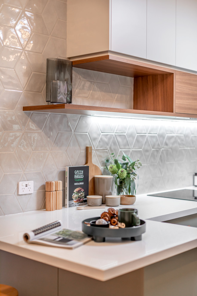Photo of a medium sized contemporary galley kitchen pantry in Adelaide with a submerged sink, flat-panel cabinets, green cabinets, engineered stone countertops, grey splashback, porcelain splashback, stainless steel appliances, light hardwood flooring, a breakfast bar and white worktops.