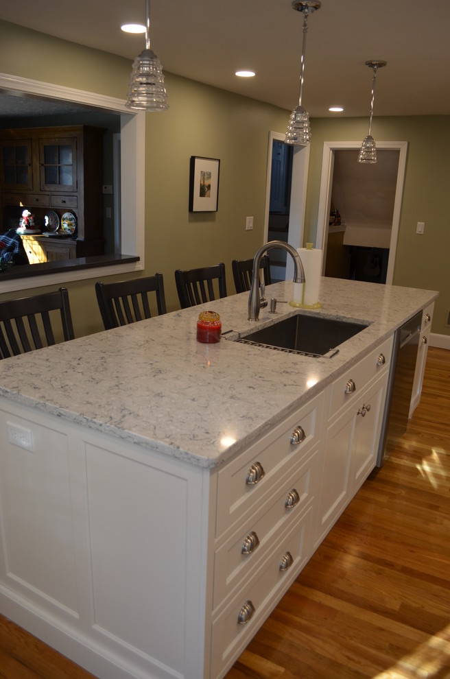 Inspiration for a transitional l-shaped light wood floor eat-in kitchen remodel in Boston with an undermount sink, beaded inset cabinets, white cabinets, quartz countertops, white backsplash, ceramic backsplash, stainless steel appliances, an island and gray countertops