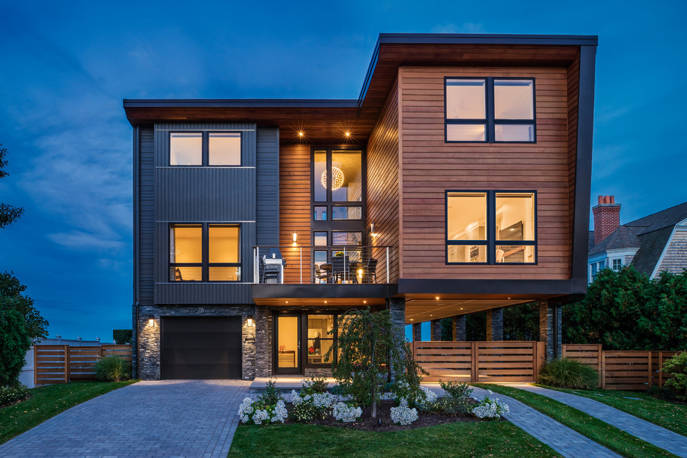 This is an example of a contemporary three-storey exterior in Providence with wood siding and a flat roof.