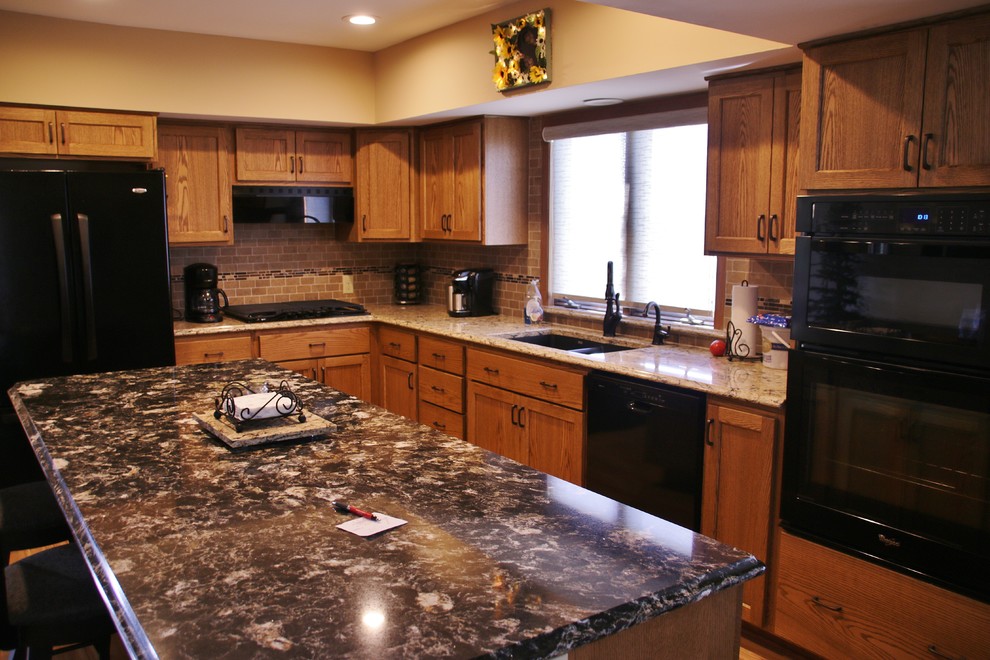 Example of a mid-sized l-shaped eat-in kitchen design with flat-panel cabinets, medium tone wood cabinets, quartz countertops, beige backsplash, black appliances and an island