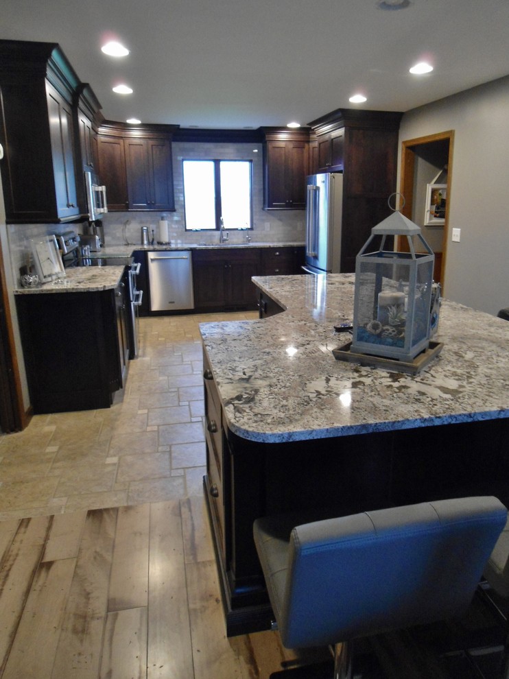 Inspiration for a mid-sized transitional u-shaped eat-in kitchen remodel with an undermount sink, flat-panel cabinets, dark wood cabinets, granite countertops, gray backsplash, subway tile backsplash, stainless steel appliances and an island