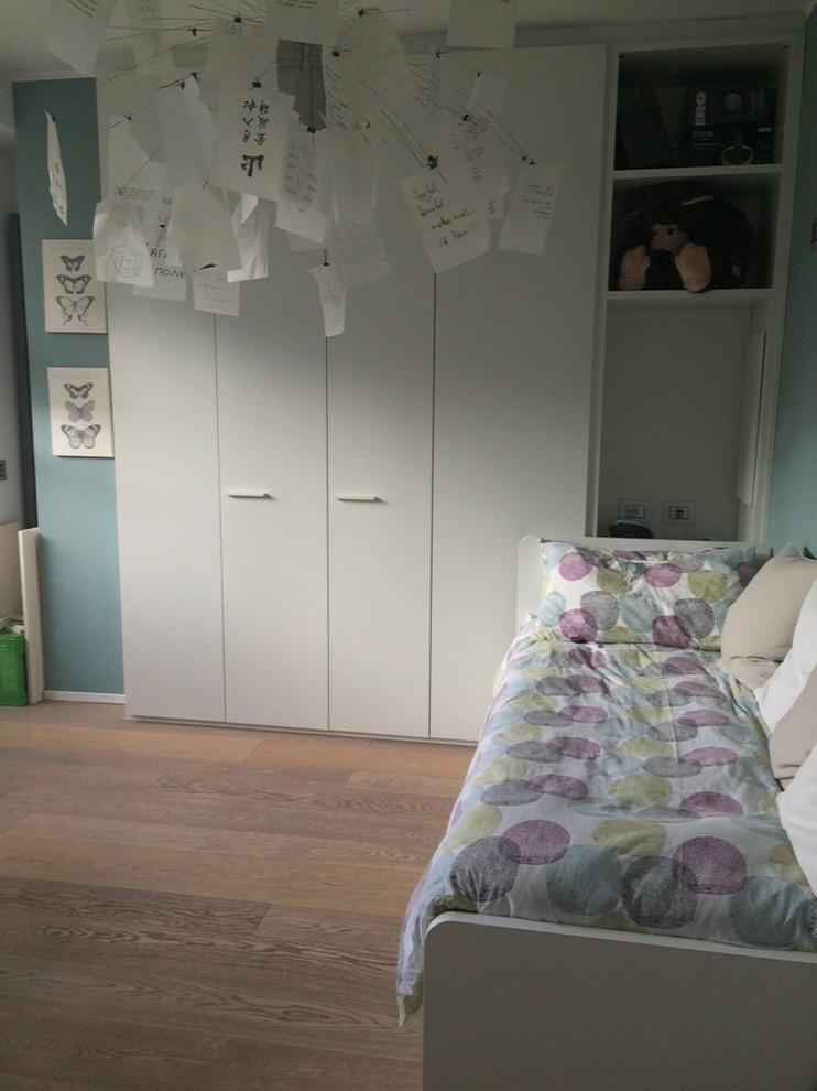 Mid-sized modern gender-neutral kids' room in Milan with white walls, light hardwood floors and brown floor.