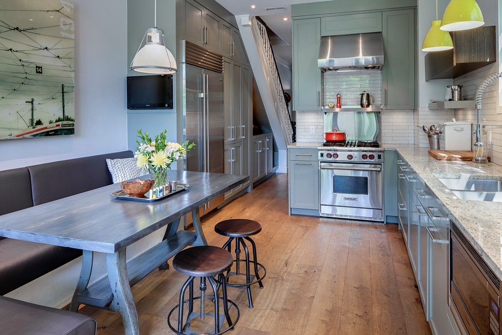 This is an example of a mid-sized traditional l-shaped separate kitchen in Toronto with granite benchtops, a double-bowl sink, shaker cabinets, green cabinets, white splashback, porcelain splashback, stainless steel appliances, light hardwood floors and no island.