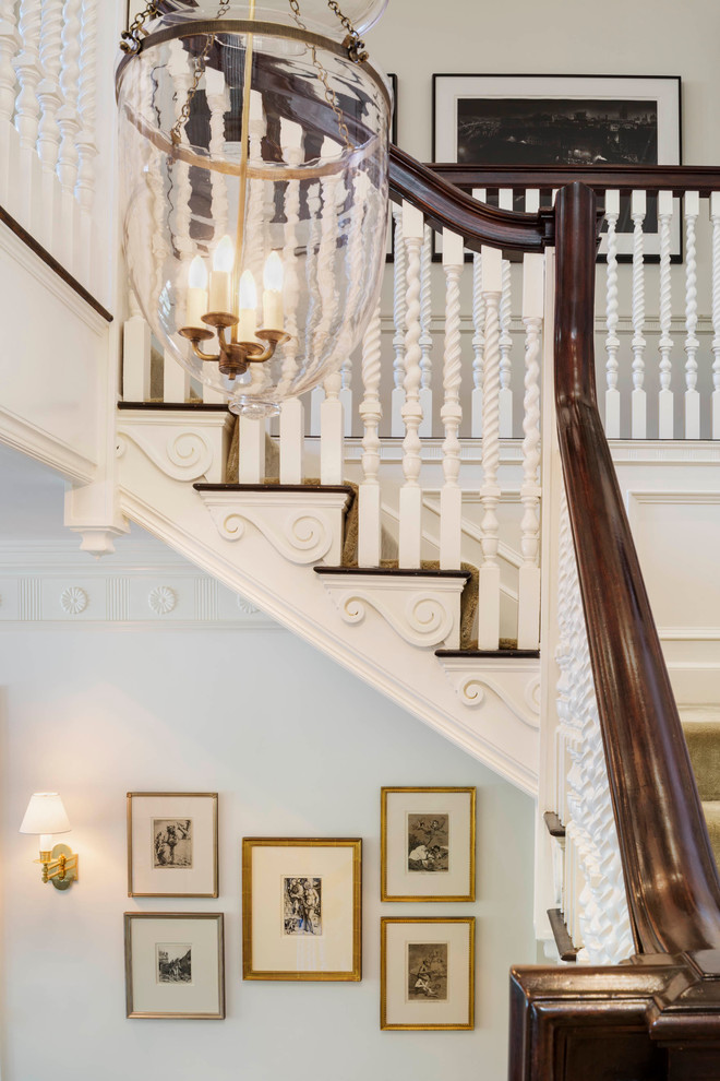 Mid-sized traditional carpeted u-shaped staircase in Boston with carpet risers and wood railing.