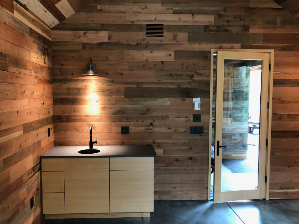 Example of a single-wall concrete floor and gray floor open concept kitchen design with a drop-in sink, light wood cabinets and wood backsplash