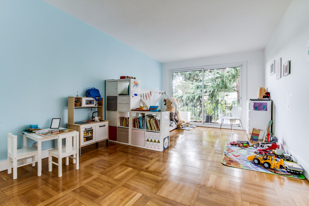 This is an example of a large contemporary kids' room for kids 4-10 years old in Paris with blue walls, light hardwood floors and beige floor.