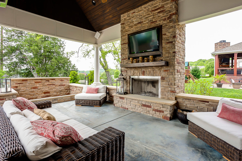 This is an example of a large traditional backyard patio in Nashville with concrete slab, a roof extension and with fireplace.