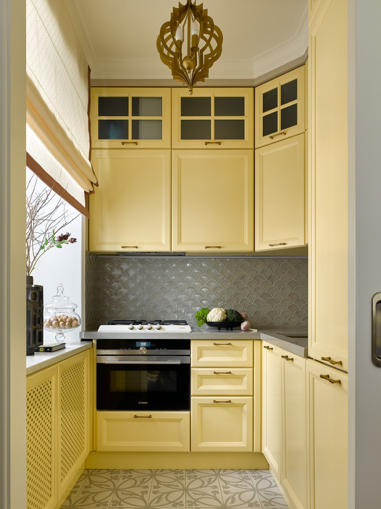 Photo of a small transitional l-shaped separate kitchen in Moscow with an undermount sink, recessed-panel cabinets, yellow cabinets, grey splashback, panelled appliances, no island, grey floor and grey benchtop.