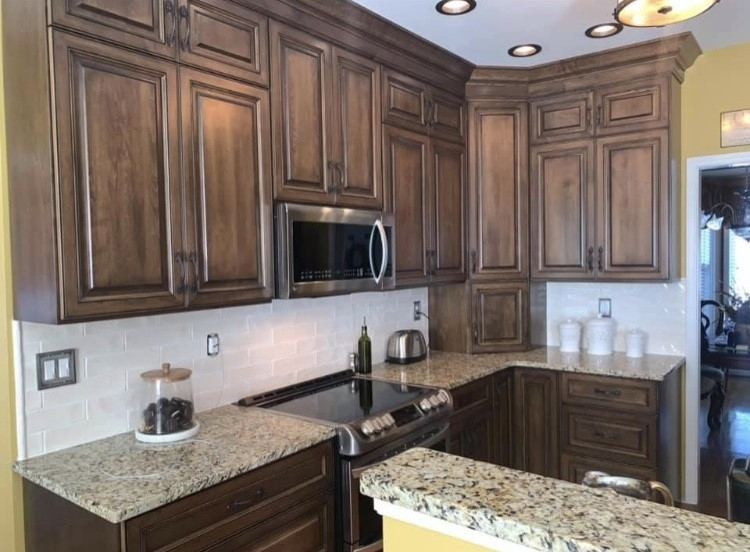 Photo of a mid-sized traditional single-wall eat-in kitchen in Other with an undermount sink, raised-panel cabinets, dark wood cabinets, granite benchtops, ceramic splashback, stainless steel appliances, light hardwood floors, with island, beige benchtop and recessed.