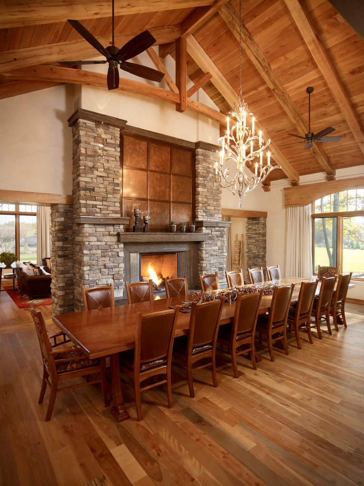 Inspiration for a country dining room in Toronto with beige walls, medium hardwood floors, a standard fireplace and a stone fireplace surround.