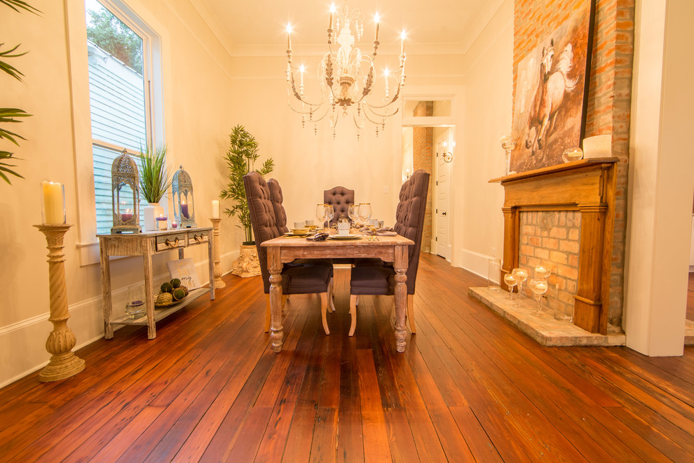 Photo of a mid-sized traditional separate dining room in New Orleans with white walls, dark hardwood floors, a standard fireplace and a brick fireplace surround.
