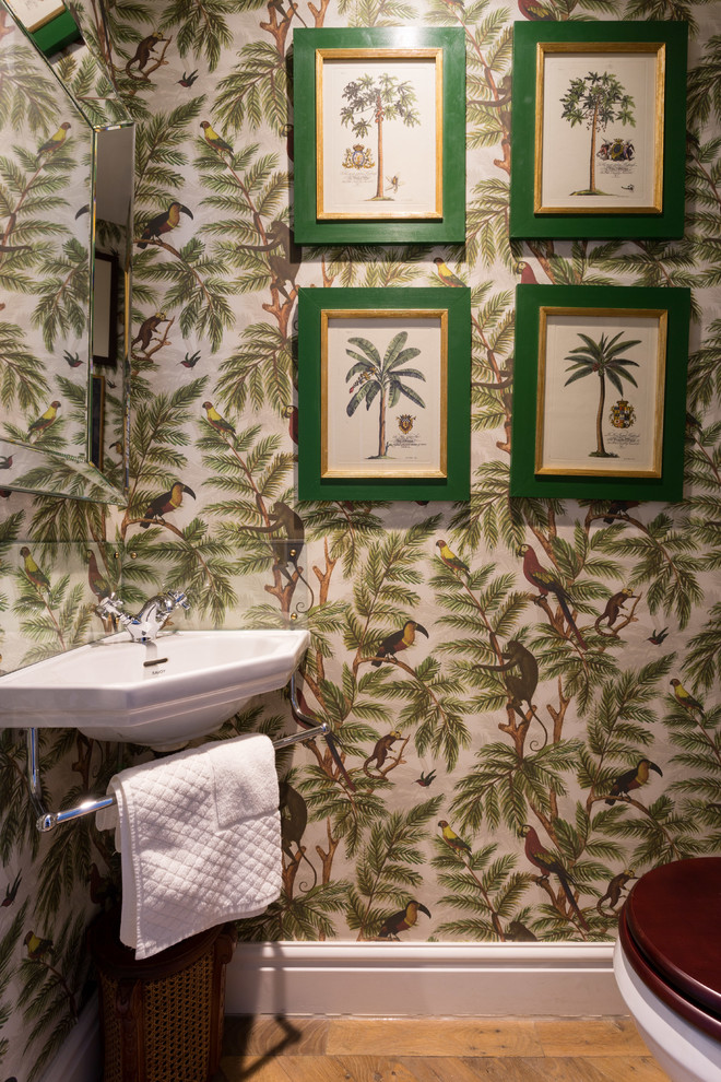 Photo of a small tropical powder room in London with light hardwood floors, a wall-mount sink, beige floor and multi-coloured walls.