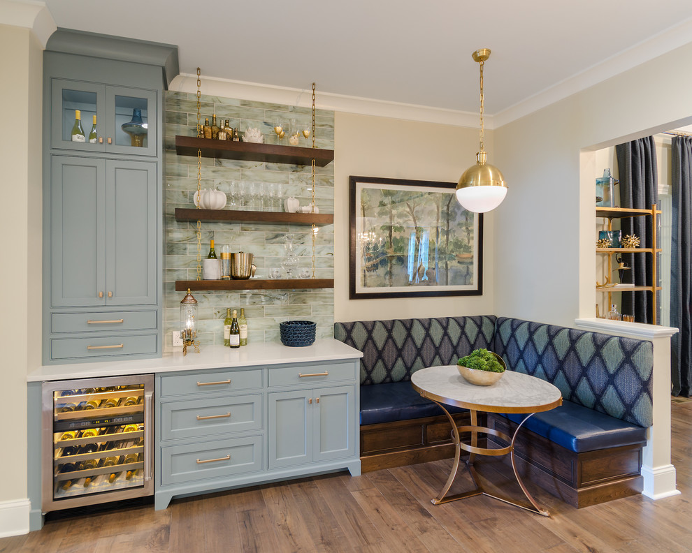Mid-sized traditional l-shaped home bar in Richmond with an undermount sink, beaded inset cabinets, blue cabinets, quartz benchtops, multi-coloured splashback, glass tile splashback and medium hardwood floors.