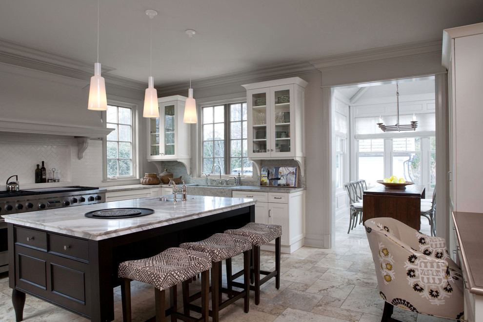 This is an example of a large traditional l-shaped eat-in kitchen in Chicago with an integrated sink, glass-front cabinets, white cabinets, marble benchtops, white splashback, stone tile splashback, stainless steel appliances, travertine floors and with island.