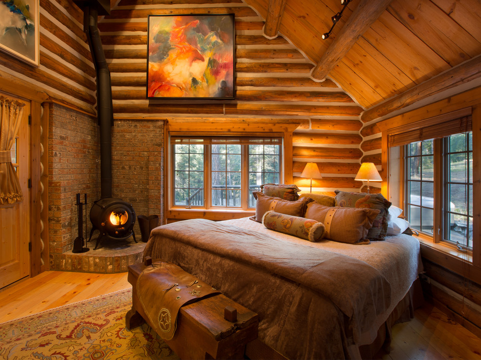Design ideas for a large country master bedroom in Other with light hardwood floors, a wood stove and a brick fireplace surround.