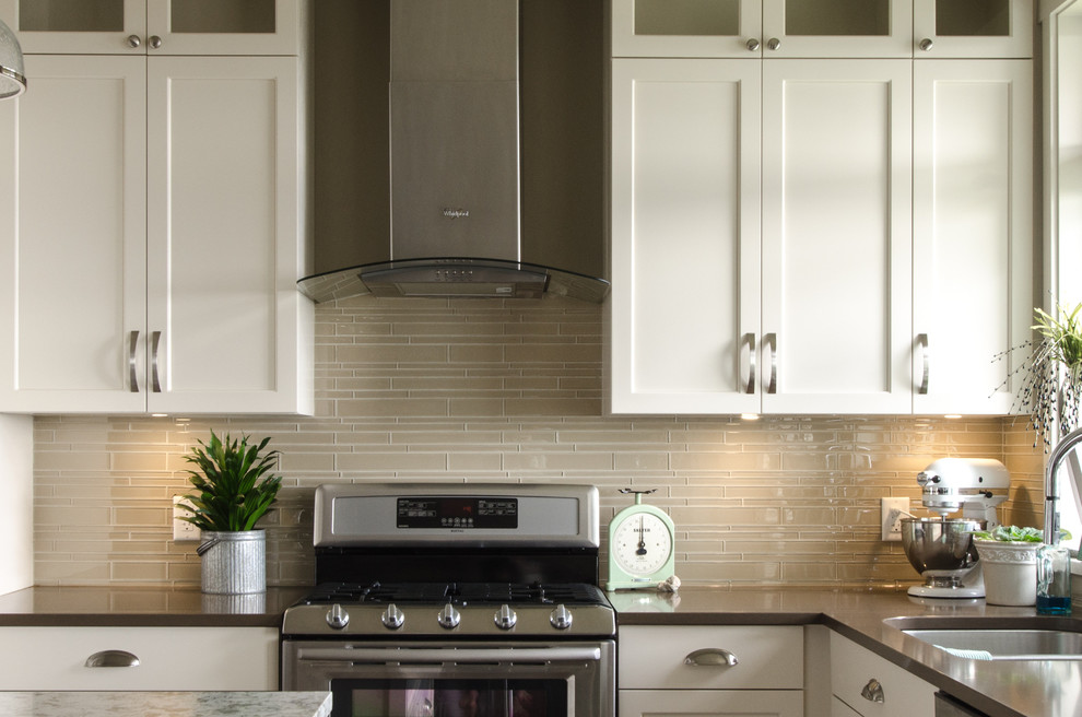 Eclectic eat-in kitchen photo in Vancouver with recessed-panel cabinets, white cabinets, quartzite countertops, beige backsplash, glass tile backsplash, stainless steel appliances and an island