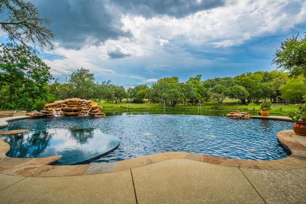 Inspiration for a transitional backyard custom-shaped infinity pool in Austin with a hot tub and concrete slab.