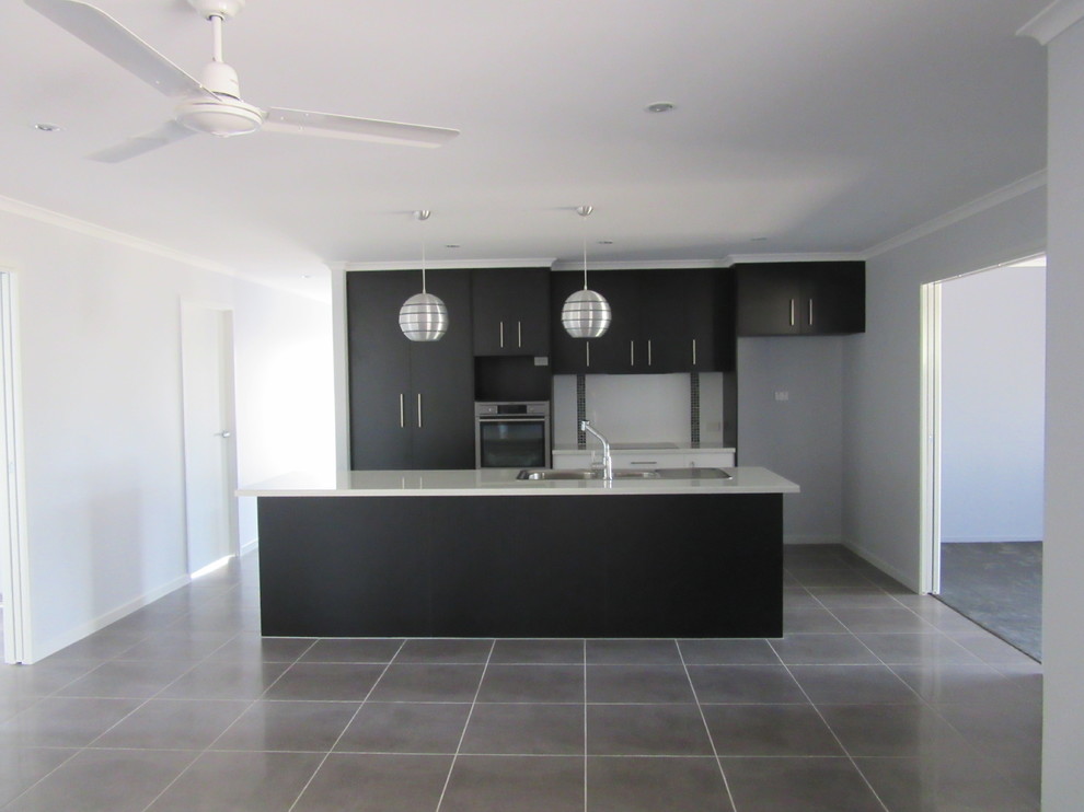 This is an example of a mid-sized modern galley eat-in kitchen in Brisbane with a double-bowl sink, dark wood cabinets, laminate benchtops, white splashback, cement tile splashback, stainless steel appliances, ceramic floors and with island.