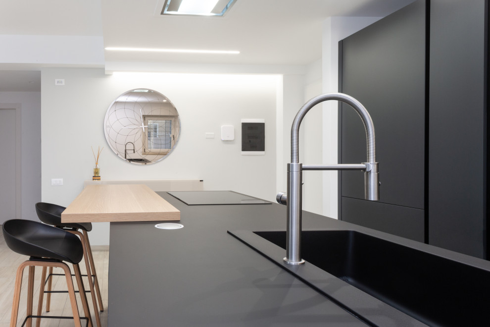 Design ideas for a medium sized modern galley open plan kitchen in Rome with a built-in sink, flat-panel cabinets, black cabinets, quartz worktops, black splashback, stainless steel appliances, porcelain flooring, an island, beige floors, black worktops and a drop ceiling.