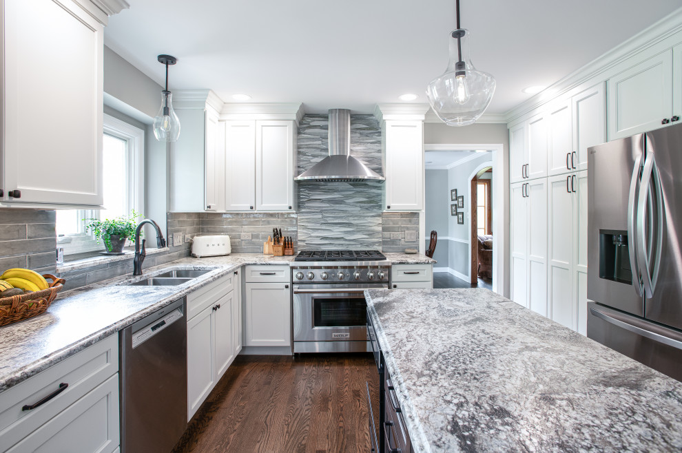 Inspiration for a mid-sized transitional u-shaped dark wood floor and brown floor open concept kitchen remodel in Chicago with a double-bowl sink, shaker cabinets, white cabinets, quartz countertops, blue backsplash, porcelain backsplash, stainless steel appliances, an island and gray countertops