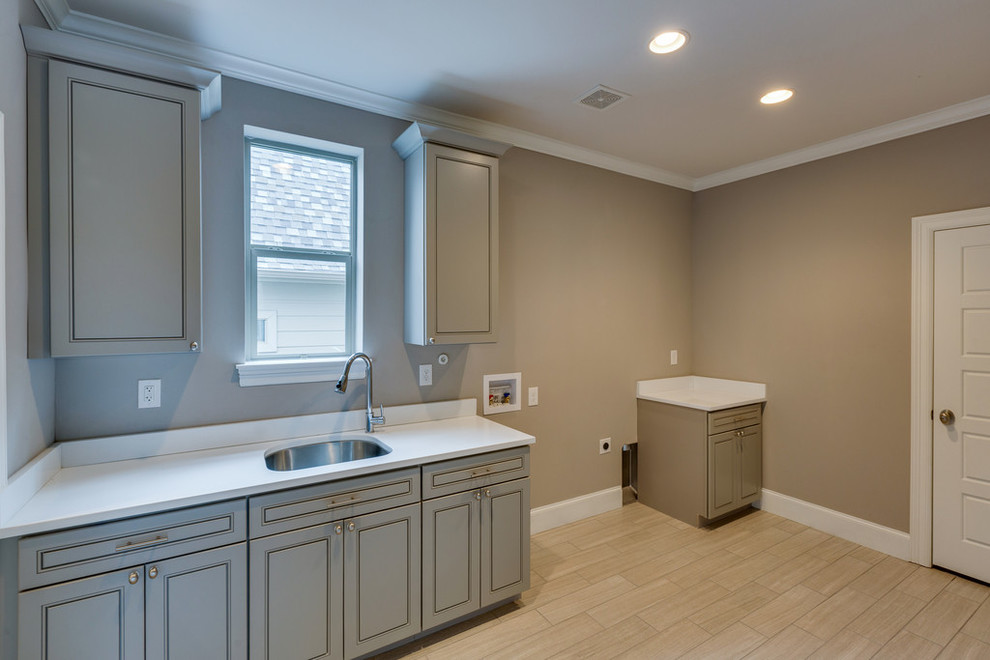 Mid-sized transitional dedicated laundry room in Dallas with a drop-in sink, grey cabinets, quartzite benchtops, ceramic floors, raised-panel cabinets and beige walls.